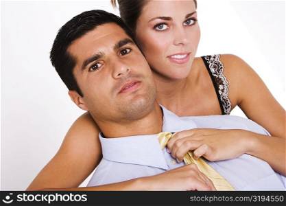Portrait of a young woman adjusting a mid adult man&acute;s tie
