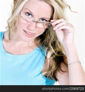 Portrait of a young woman adjusting her eyeglasses