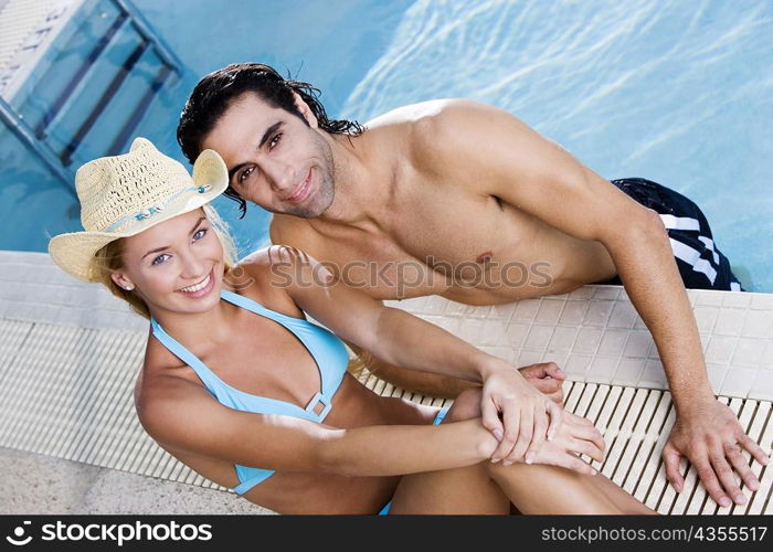 Portrait of a young woman and a mid adult man at the poolside