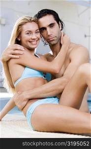Portrait of a young woman and a mid adult man embracing at the poolside