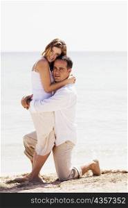 Portrait of a young woman and a mid adult man embracing each other on the beach