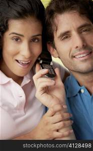 Portrait of a young woman and a mid adult man holding a mobile phone