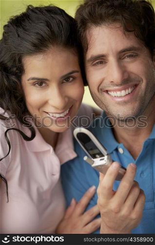 Portrait of a young woman and a mid adult man holding a mobile phone
