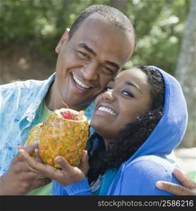 Portrait of a young woman and a mid adult man holding pineapples