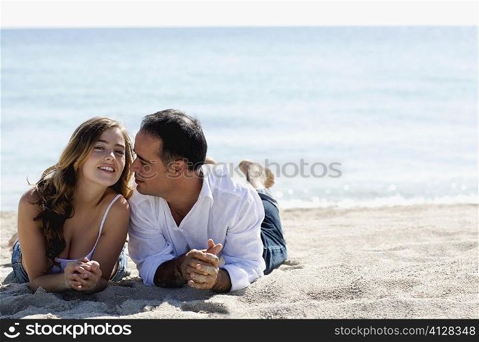 Portrait of a young woman and a mid adult man lying on the beach