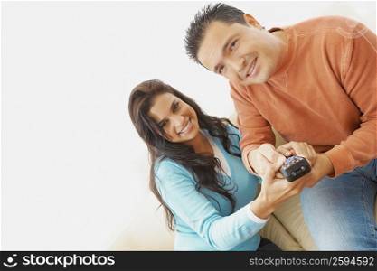 Portrait of a young woman and a mid adult man operating a remote control