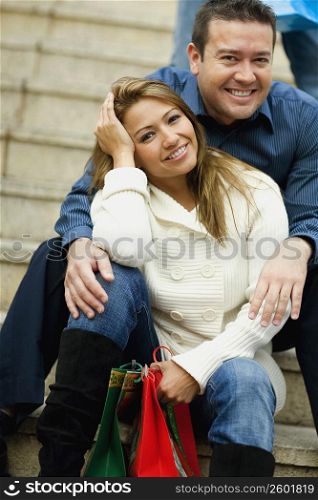Portrait of a young woman and a mid adult man sitting on the steps and smiling