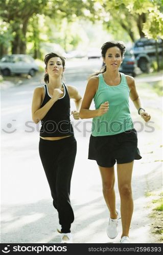 Portrait of a young woman and a mid adult woman jogging on the road
