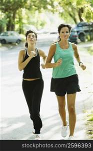Portrait of a young woman and a mid adult woman jogging on the road