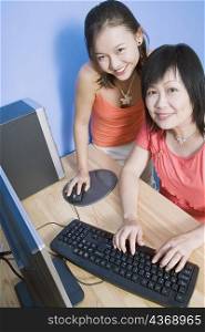 Portrait of a young woman and her mother using a computer and smiling