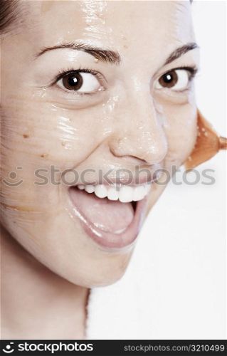 Portrait of a young woman applying a facial mask