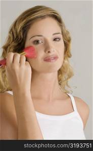 Portrait of a young woman applying blush on her cheek