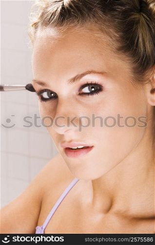 Portrait of a young woman applying eyeshadow