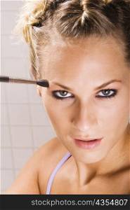 Portrait of a young woman applying eyeshadow