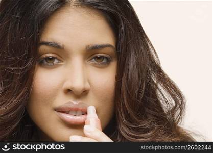 Portrait of a young woman applying lip gloss