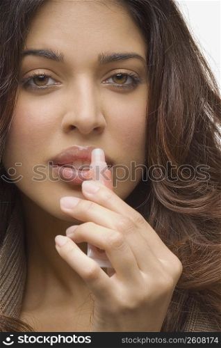 Portrait of a young woman applying lip gloss