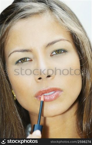Portrait of a young woman applying lip liner