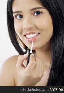 Portrait of a young woman applying lipstick