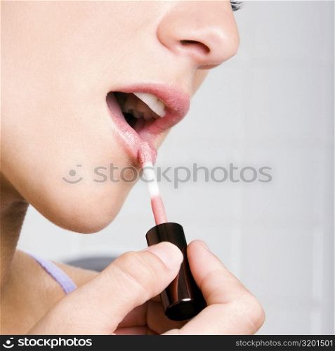 Portrait of a young woman applying lipstick