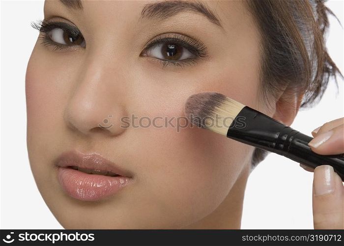 Portrait of a young woman applying make-up
