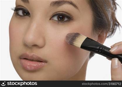 Portrait of a young woman applying make-up