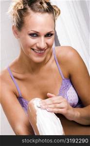 Portrait of a young woman applying shaving cream on her legs