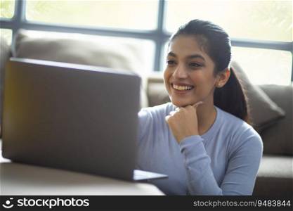 PORTRAIT OF A YOUNG WOMAN ATTENDING ONLINE CLASS AT HOME