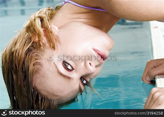 Portrait of a young woman bending forward with her hair in a swimming pool