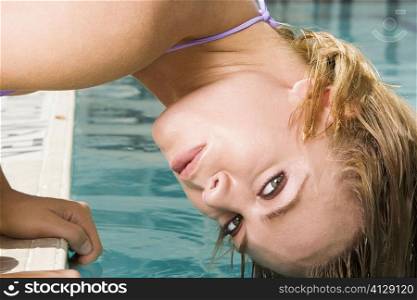 Portrait of a young woman bending forward with her hair in a swimming pool