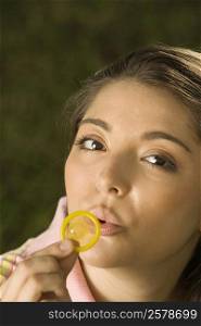 Portrait of a young woman blowing a condom