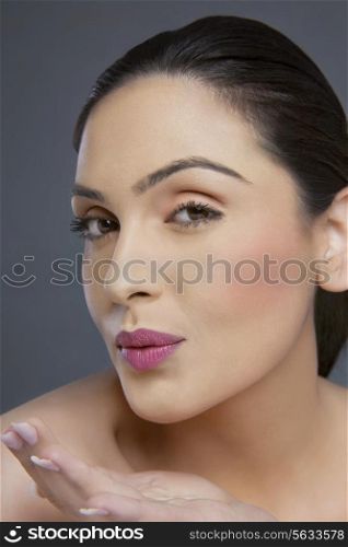 Portrait of a young woman blowing a kiss over colored background