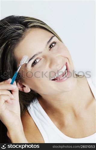 Portrait of a young woman brushing her eyebrows and smiling