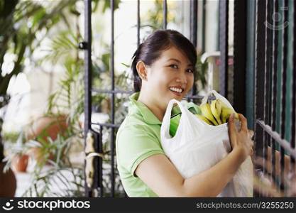 Portrait of a young woman carrying a plastic bag with bananas
