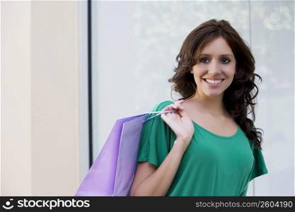 Portrait of a young woman carrying a shopping bag and smiling