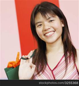 Portrait of a young woman carrying a shopping bag and smiling