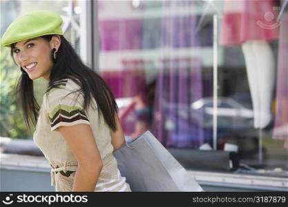 Portrait of a young woman carrying a shopping bag in front of a clothing store