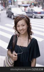 Portrait of a young woman carrying a shoulder bag and smiling