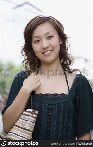 Portrait of a young woman carrying a shoulder bag and smiling