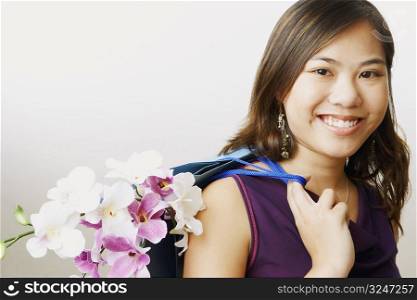 Portrait of a young woman carrying flowers in a shopping bag