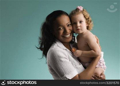 Portrait of a young woman carrying her daughter and smiling