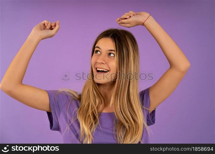 Portrait of a young woman celebrating and dancing against an isolated background.