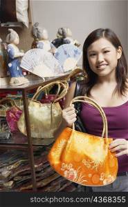 Portrait of a young woman choosing a hand bag and smiling