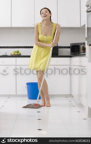 Portrait of a young woman cleaning the floor with a mop