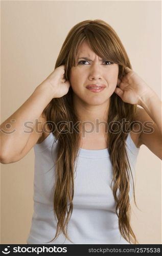 Portrait of a young woman covering her ears with her hands