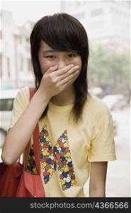 Portrait of a young woman covering her mouth with her hand