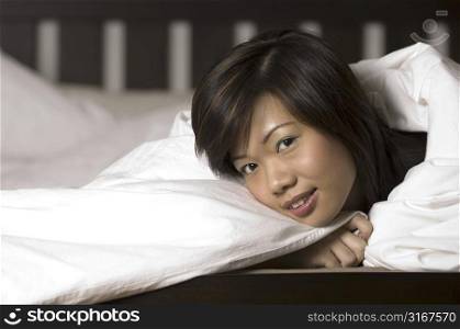 Portrait of a young woman covering herself with a duvet