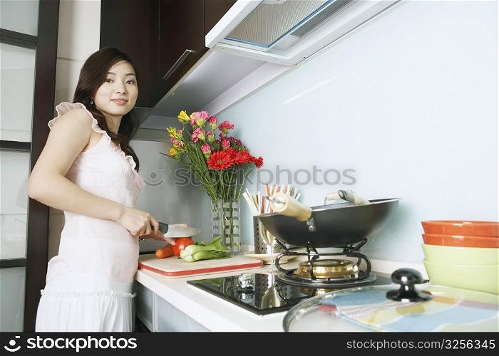 Portrait of a young woman cutting vegetables