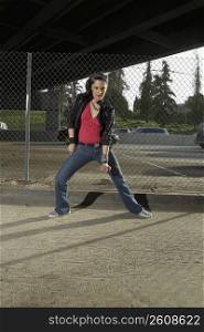 Portrait of a young woman dancing in front of a chain-link fence