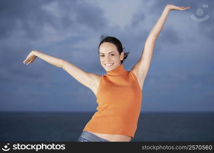 Portrait of a young woman dancing with her arms raised