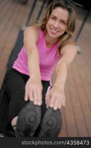 Portrait of a young woman doing sit-ups and touching her toes